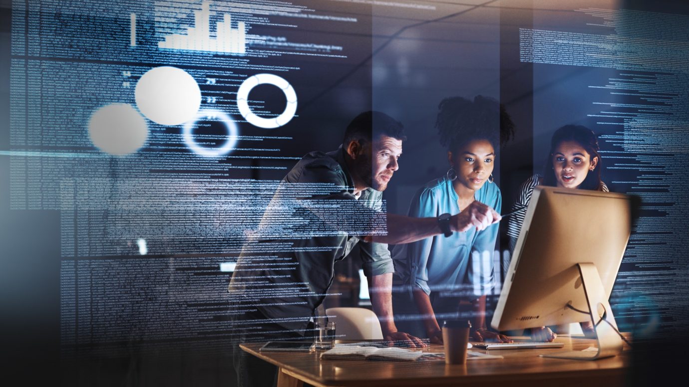 group of programmers working together on a computer code at night