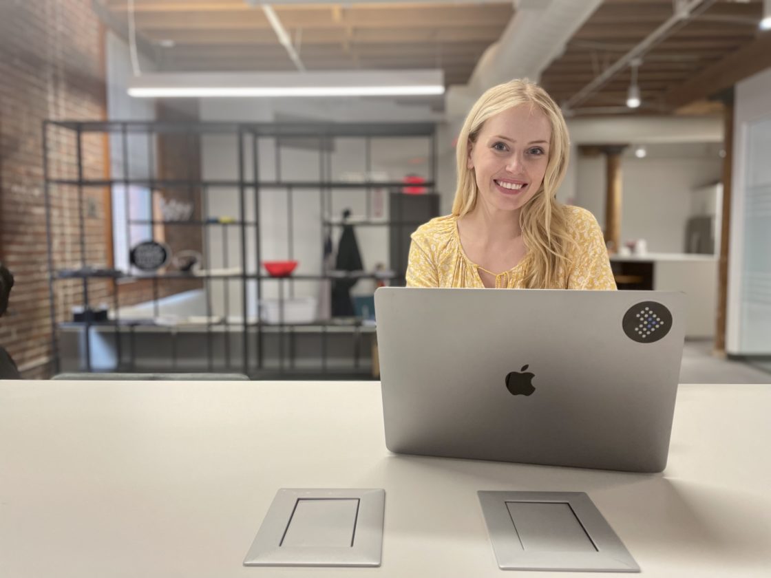 Woman smiling behind her laptop